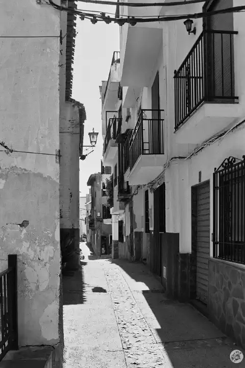 A black-and-white photo of a narrow street in Soportújar with white houses on both sides.