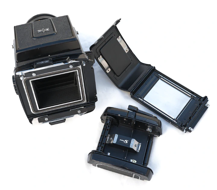 A photo of the Mamiya RB67 with the film back removed from the camera body and disassembled.