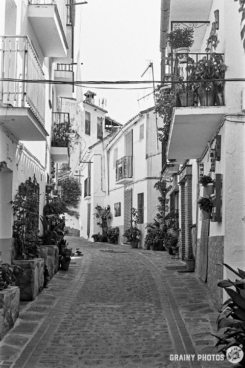 A black-and-white film photo of a narrow street in a Spanish White village. This photo was taken with the Pentax MX camera.