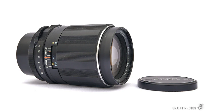 A photo of the Super-Takumar 135mm lens lying on its side.