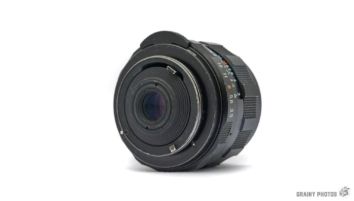 A photo of the Super-Takumar 28mm f3.5 lens on its side with the M42 threaded end foremost.