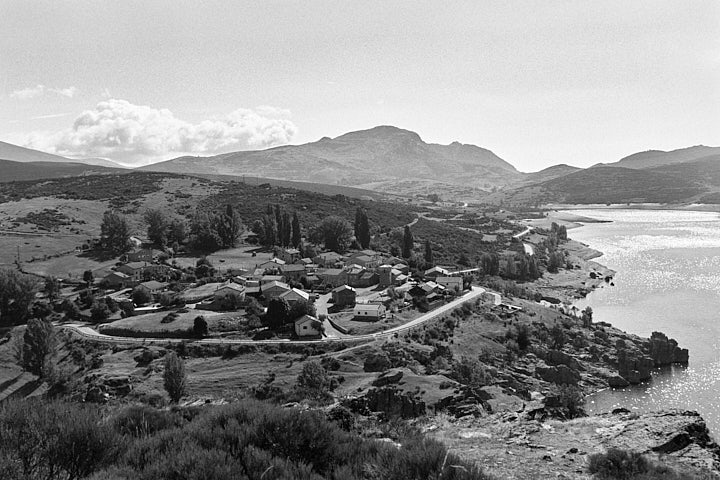 A black-and-white film photo of Alba de los Cardaños by the reservoir