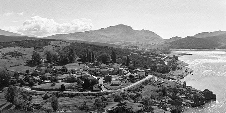 A black-and-white film photo of Alba de los Cardaños by the reservoir