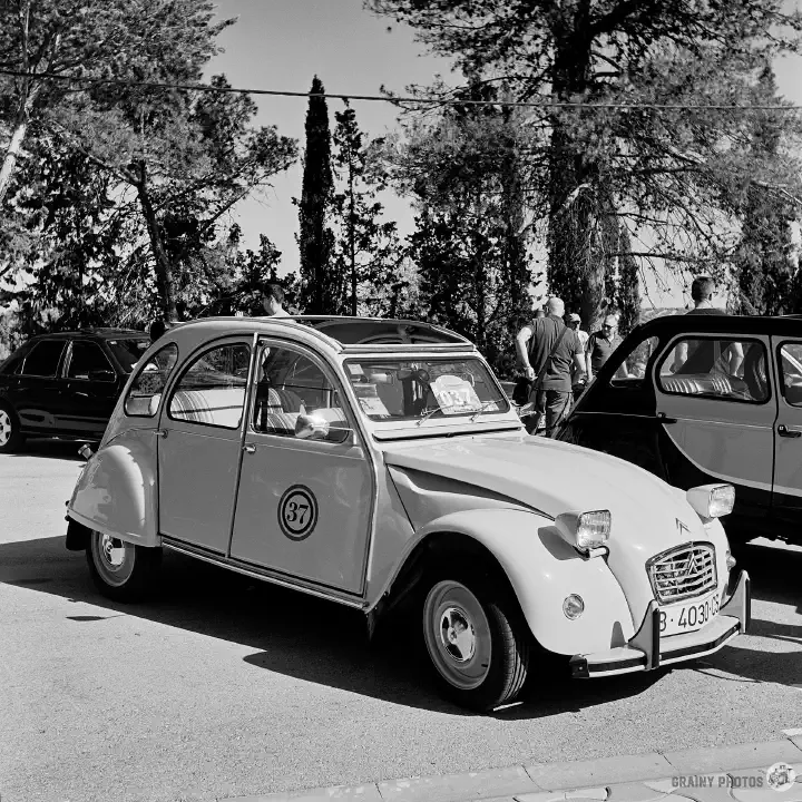 Black-and-white film photo of a Citroen 2CV