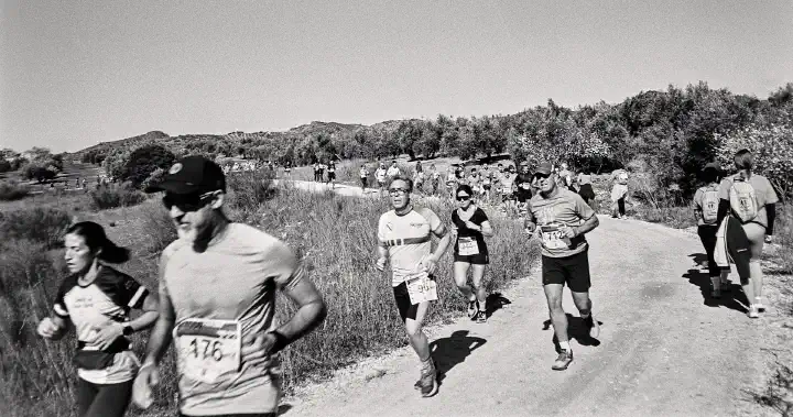 More runners pass the walkers going in the opposite direction on a dirt track by the reservoir.
