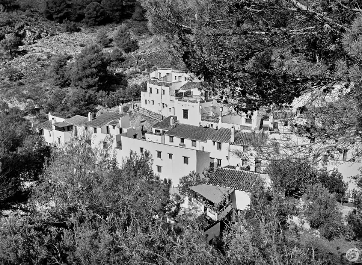 A black-and-white film photo of El Acebuchal nestling on the side of the valley