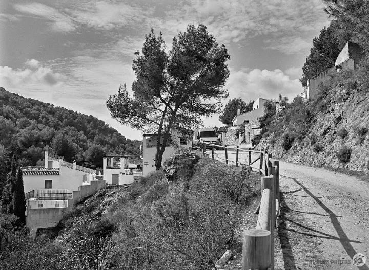 A black-and-white film photo of El Acebuchal approaching from Frigiliana