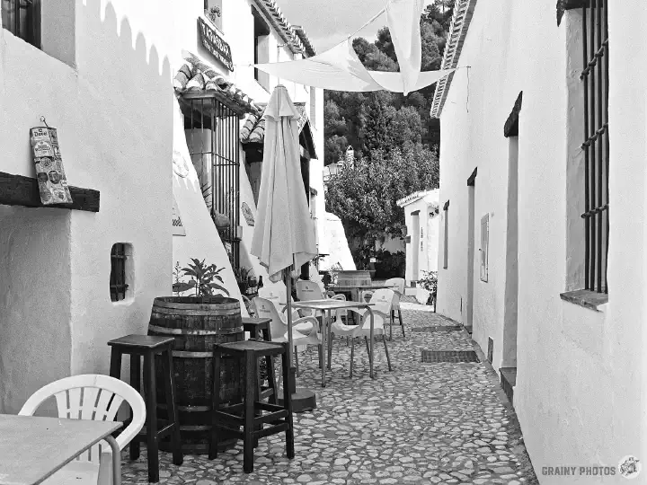 A black-and-white film photo of a tapas bar in the village