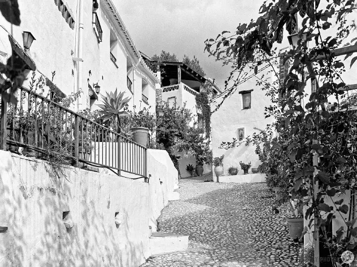 A black-and-white film photo of a cobbled street in the village