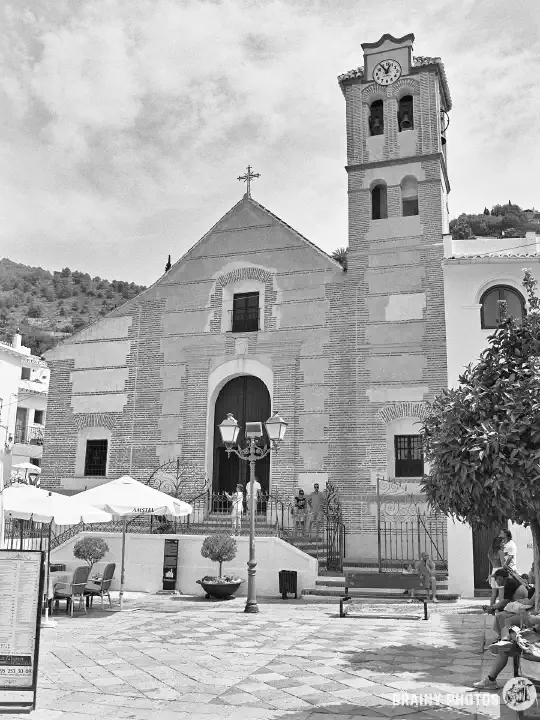 A black-and-white photo of Iglesia de San Antonio de Padua. In front of the church is a town square.