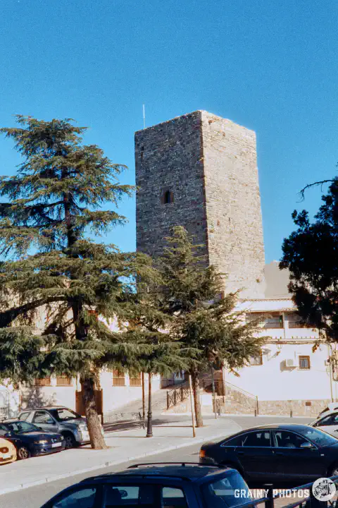 A colour film photo of a castle tower with a car park in the foreground. Shot on Harman Phoenix 200 film.