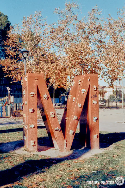 A colour film photo of a climbing frame in the shape of a big letter 