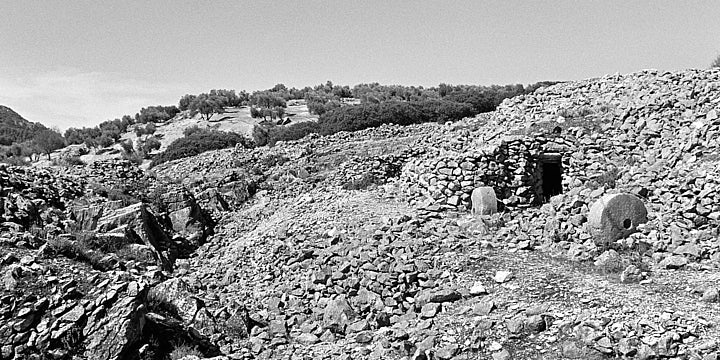 A black-and-white film photo of the abandoned stonemason settlement at Los Caracoles