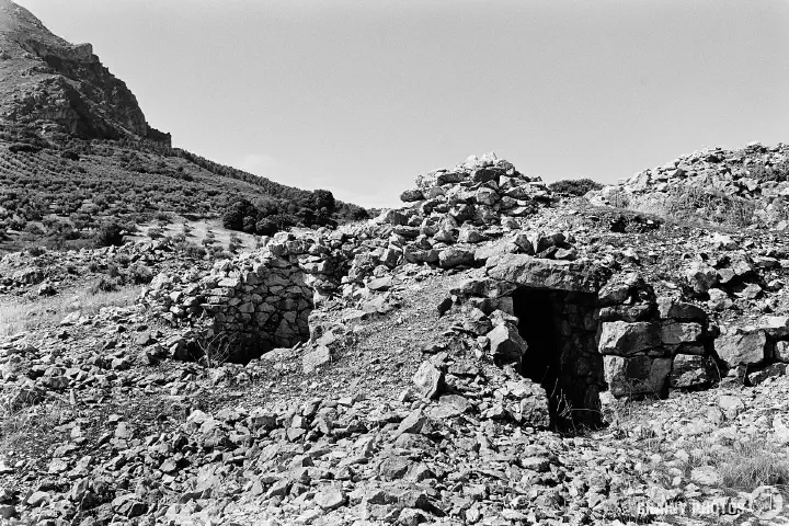 Black-and-white photo of the entrance to the remains of one of the stonemason's huts on the site.