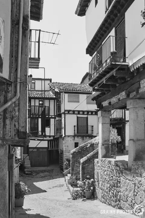 A black-and-white film photo of a narrow street in Mogarraz.
