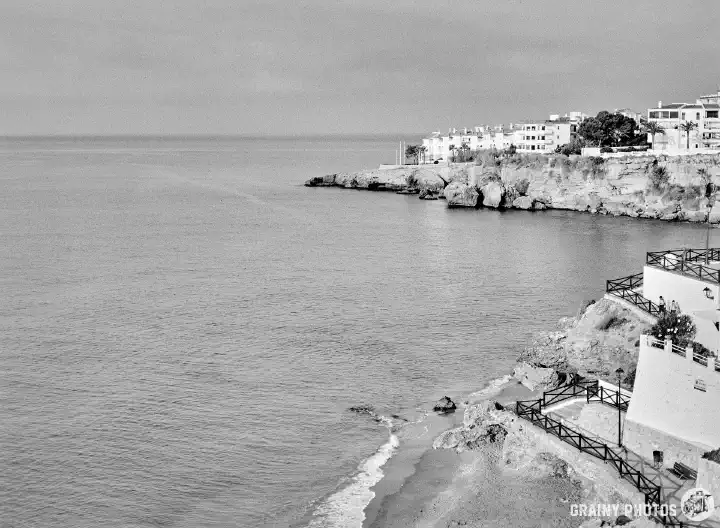 A black and white film photo of the Nerja coastline and sea taken from Balcon de Europa