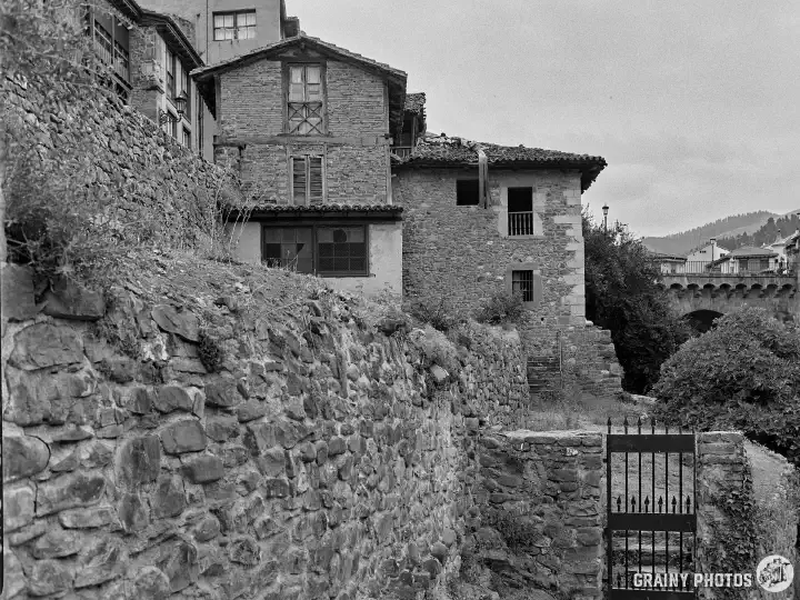 A black-and-white film photo of traditional masonry, constructed houses in the old part of Potes.