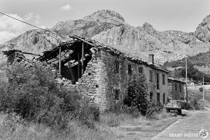 A black-and-white film photo of abandoned terraced houses