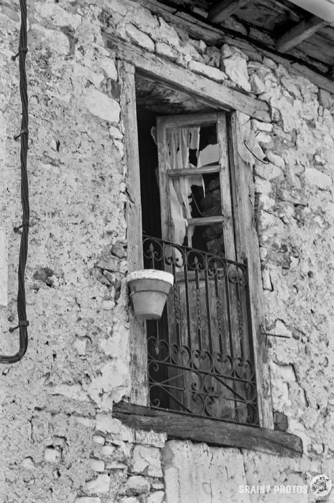 A black-and-white film photo of a Juliette balcony in an abandoned house