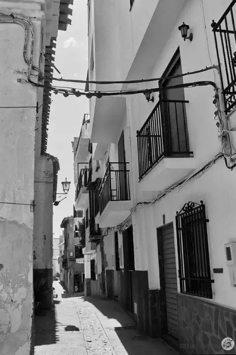 A black-and-white photo of a narrow street in Soportújar with white houses on both sides.