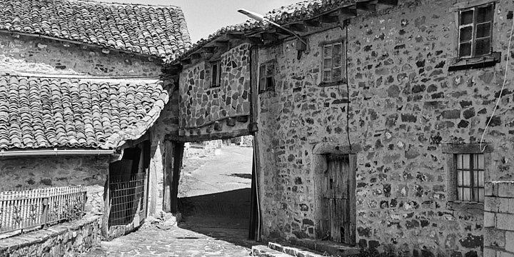 A black-and-white film photo of on old stone house with a tinao in the village of Verdeña, Palencia, Spain