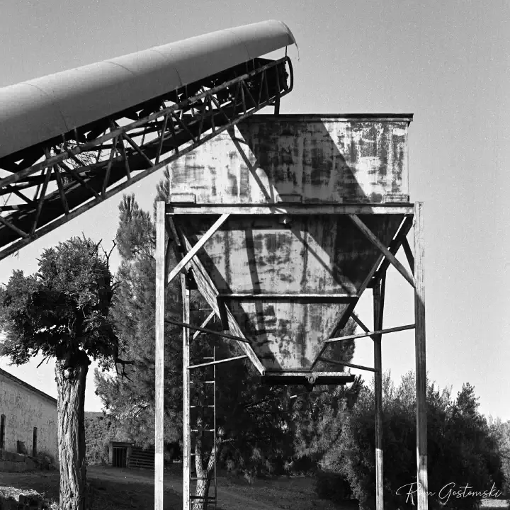 A more detailed black-and-white film photo showing the conveyor belt leading up to the hopper