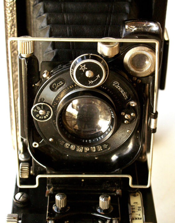 A close-up of an ICA Lloyd 510 camera featuring a large lens with the word "COMPURE" embossed on it, various dials for settings, and a classic bellows design, all showcasing intricate vintage craftsmanship.