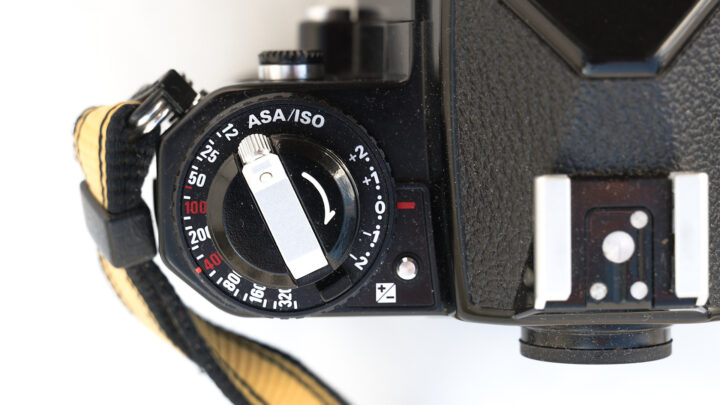 Top view of a vintage Nikon FE2 film camera showing the ASA/ISO dial and strap, highlighting settings for film sensitivity. The design features classic elements, suggesting a focus on manual photography and traditional film use.